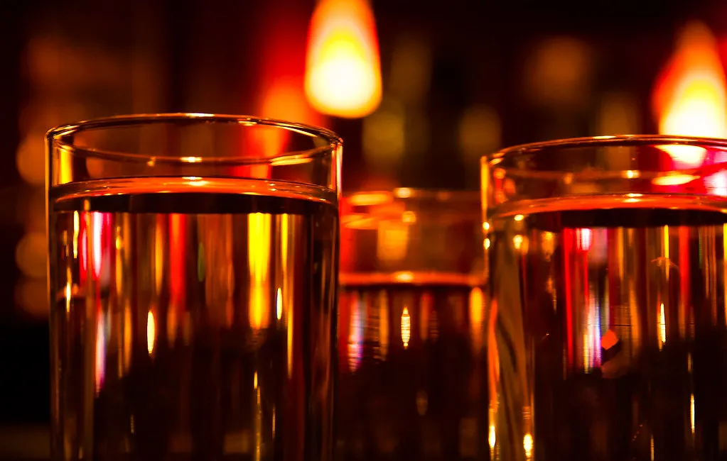 Glass som gløder i gult og oransje fra levende lys i baren